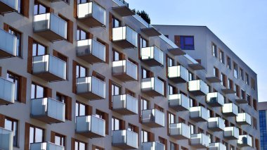 Şehirde simetrik modern mimarisi olan bir apartman. Güneşli bir günde modern apartman binası. Modern bir apartmanın ön cephesi. Alt görünüm. 