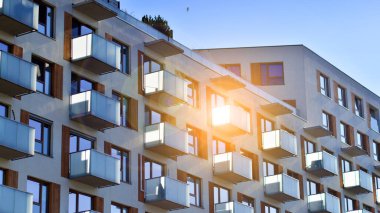 Şehirde simetrik modern mimarisi olan bir apartman. Güneşli bir günde modern apartman binası. Modern bir apartmanın ön cephesi. Alt görünüm. 