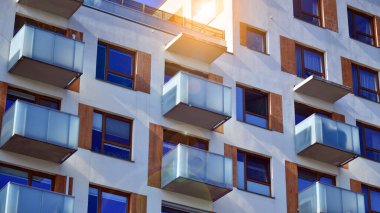 Şehirde simetrik modern mimarisi olan bir apartman. Güneşli bir günde modern apartman binası. Modern bir apartmanın ön cephesi. Alt görünüm. 