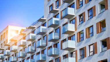 Şehirde simetrik modern mimarisi olan bir apartman. Güneşli bir günde modern apartman binası. Modern bir apartmanın ön cephesi. Alt görünüm. 