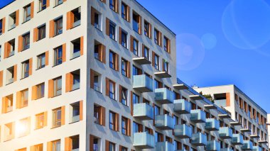 Şehirde simetrik modern mimarisi olan bir apartman. Güneşli bir günde modern apartman binası. Modern bir apartmanın ön cephesi. Alt görünüm. 