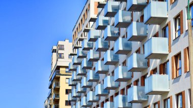 Şehirde simetrik modern mimarisi olan bir apartman. Güneşli bir günde modern apartman binası. Modern bir apartmanın ön cephesi. Alt görünüm. 