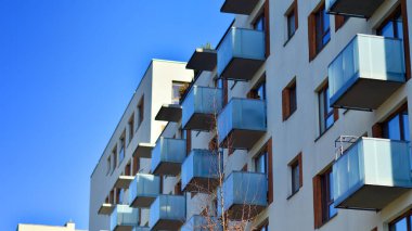 Şehirde simetrik modern mimarisi olan bir apartman. Güneşli bir günde modern apartman binası. Modern bir apartmanın ön cephesi. Alt görünüm. 