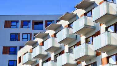 Şehirde simetrik modern mimarisi olan bir apartman. Güneşli bir günde modern apartman binası. Modern bir apartmanın ön cephesi. Alt görünüm. 