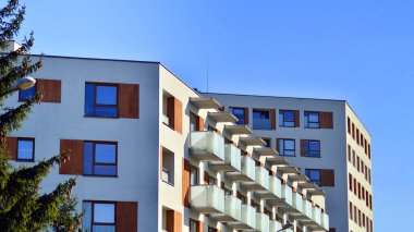 Şehirde simetrik modern mimarisi olan bir apartman. Güneşli bir günde modern apartman binası. Modern bir apartmanın ön cephesi. Alt görünüm. 