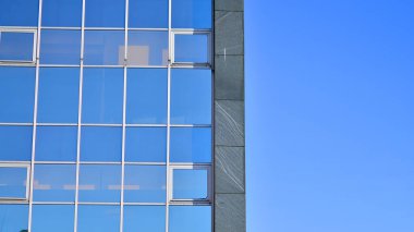 Yapısal cam duvar mavi gökyüzünü yansıtıyor. Soyut modern mimari parçası. Binanın şeffaf yüzüyle cam bina ve mavi gökyüzü. Çağdaş mimari arka plan.