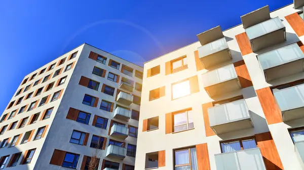 Şehirde simetrik modern mimarisi olan bir apartman. Güneşli bir günde modern apartman binası. Modern bir apartmanın ön cephesi. Alt görünüm. 