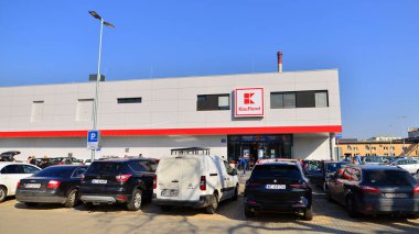 Varşova, Polonya. 6 Mart 2025. Logosu ve markası Kaufland mağazası olan bir tabela. Bir süpermarkete giriş ve müşteri arabaları park halinde..