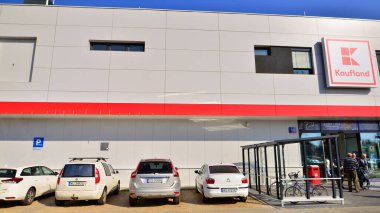 Varşova, Polonya. 6 Mart 2025. Logosu ve markası Kaufland mağazası olan bir tabela. Bir süpermarkete giriş ve müşteri arabaları park halinde..