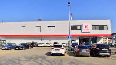Varşova, Polonya. 6 Mart 2025. Logosu ve markası Kaufland mağazası olan bir tabela. Bir süpermarkete giriş ve müşteri arabaları park halinde..