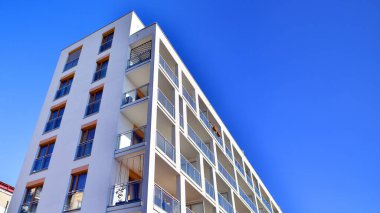 Şehirde simetrik modern mimarisi olan bir apartman. Güneşli bir günde modern apartman binası. Modern bir apartmanın ön cephesi. Alt görünüm. 