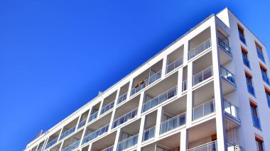 Şehirde simetrik modern mimarisi olan bir apartman. Güneşli bir günde modern apartman binası. Modern bir apartmanın ön cephesi. Alt görünüm. 