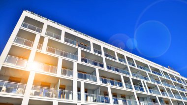 Şehirde simetrik modern mimarisi olan bir apartman. Güneşli bir günde modern apartman binası. Modern bir apartmanın ön cephesi. Alt görünüm. 