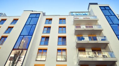 Şehirde simetrik modern mimarisi olan bir apartman. Güneşli bir günde modern apartman binası. Modern bir apartmanın ön cephesi. Alt görünüm. 