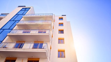 Şehirde simetrik modern mimarisi olan bir apartman. Güneşli bir günde modern apartman binası. Modern bir apartmanın ön cephesi. Alt görünüm. 