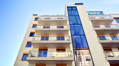 Şehirde simetrik modern mimarisi olan bir apartman. Güneşli bir günde modern apartman binası. Modern bir apartmanın ön cephesi. Alt görünüm. 