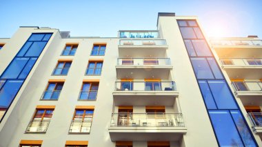 Şehirde simetrik modern mimarisi olan bir apartman. Güneşli bir günde modern apartman binası. Modern bir apartmanın ön cephesi. Alt görünüm. 