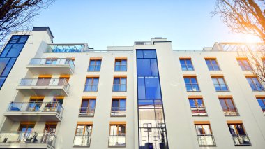 Şehirde simetrik modern mimarisi olan bir apartman. Güneşli bir günde modern apartman binası. Modern bir apartmanın ön cephesi. Alt görünüm. 