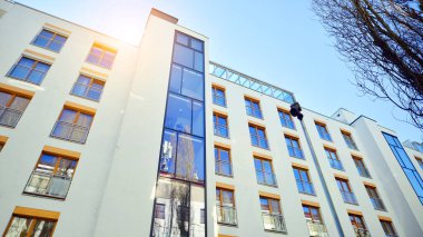 Şehirde simetrik modern mimarisi olan bir apartman. Güneşli bir günde modern apartman binası. Modern bir apartmanın ön cephesi. Alt görünüm. 