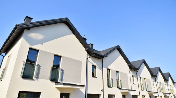 Рынок недвижимости в пригороде. Новые односемейные дома в новом районе застройки. Жилые дома с современным фасадом. Семейные дома с террасами в недавно построенном жилом комплексе. 