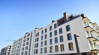 Şehirde simetrik modern mimarisi olan bir apartman. Güneşli bir günde modern apartman binası. Modern bir apartmanın ön cephesi. Alt görünüm. 