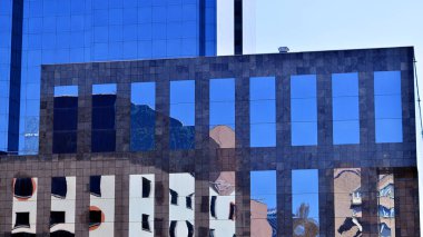 Şehir merkezindeki işletme bölgesi mimarisi. Mavi gökyüzüne ve güneş ışığına karşı cam yansıtıcı ofis binaları. Ekonomi, finans, iş faaliyeti konsepti. Ufukta yükselen güneş.