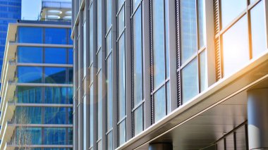 Şehir merkezindeki işletme bölgesi mimarisi. Mavi gökyüzüne ve güneş ışığına karşı cam yansıtıcı ofis binaları. Ekonomi, finans, iş faaliyeti konsepti. Ufukta yükselen güneş.