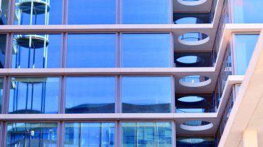 Şehir merkezindeki işletme bölgesi mimarisi. Mavi gökyüzüne ve güneş ışığına karşı cam yansıtıcı ofis binaları. Ekonomi, finans, iş faaliyeti konsepti. Ufukta yükselen güneş.