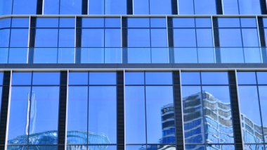 Şehir merkezindeki işletme bölgesi mimarisi. Mavi gökyüzüne ve güneş ışığına karşı cam yansıtıcı ofis binaları. Ekonomi, finans, iş faaliyeti konsepti. Ufukta yükselen güneş.