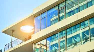 Şehir merkezindeki işletme bölgesi mimarisi. Mavi gökyüzüne ve güneş ışığına karşı cam yansıtıcı ofis binaları. Ekonomi, finans, iş faaliyeti konsepti. Ufukta yükselen güneş.