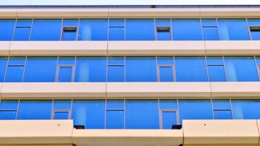 Şehir merkezindeki işletme bölgesi mimarisi. Mavi gökyüzüne ve güneş ışığına karşı cam yansıtıcı ofis binaları. Ekonomi, finans, iş faaliyeti konsepti. Ufukta yükselen güneş.