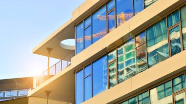 Şehir merkezindeki işletme bölgesi mimarisi. Mavi gökyüzüne ve güneş ışığına karşı cam yansıtıcı ofis binaları. Ekonomi, finans, iş faaliyeti konsepti. Ufukta yükselen güneş.