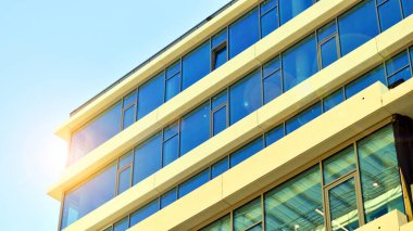 Şehir merkezindeki işletme bölgesi mimarisi. Mavi gökyüzüne ve güneş ışığına karşı cam yansıtıcı ofis binaları. Ekonomi, finans, iş faaliyeti konsepti. Ufukta yükselen güneş.