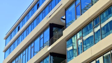 Şehir merkezindeki işletme bölgesi mimarisi. Mavi gökyüzüne ve güneş ışığına karşı cam yansıtıcı ofis binaları. Ekonomi, finans, iş faaliyeti konsepti. Ufukta yükselen güneş.