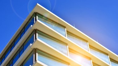 Şehir merkezindeki işletme bölgesi mimarisi. Mavi gökyüzüne ve güneş ışığına karşı cam yansıtıcı ofis binaları. Ekonomi, finans, iş faaliyeti konsepti. Ufukta yükselen güneş.