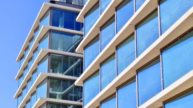 Şehir merkezindeki işletme bölgesi mimarisi. Mavi gökyüzüne ve güneş ışığına karşı cam yansıtıcı ofis binaları. Ekonomi, finans, iş faaliyeti konsepti. Ufukta yükselen güneş.