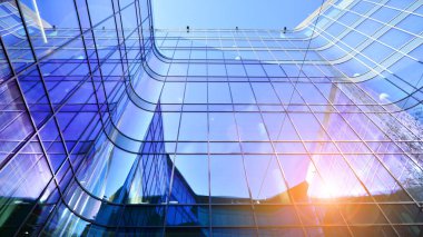 Gökyüzü arka planında cam cepheli modern ofis binası. Ofis binasının şeffaf cam duvarı.