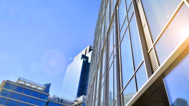Gökyüzü arka planında cam cepheli modern ofis binası. Ofis binasının şeffaf cam duvarı.