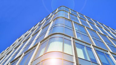 Gökyüzü arka planında cam cepheli modern ofis binası. Ofis binasının şeffaf cam duvarı.