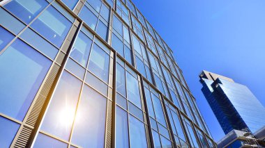 Gökyüzü arka planında cam cepheli modern ofis binası. Ofis binasının şeffaf cam duvarı.