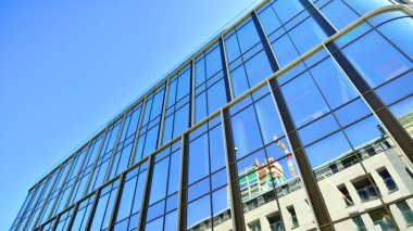 Gökyüzü arka planında cam cepheli modern ofis binası. Ofis binasının şeffaf cam duvarı.