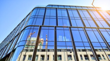 Gökyüzü arka planında cam cepheli modern ofis binası. Ofis binasının şeffaf cam duvarı.