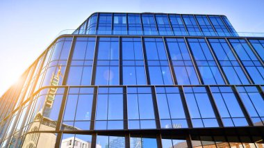 Gökyüzü arka planında cam cepheli modern ofis binası. Ofis binasının şeffaf cam duvarı.