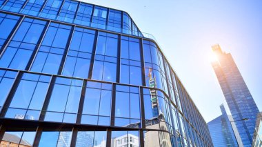 Gökyüzü arka planında cam cepheli modern ofis binası. Ofis binasının şeffaf cam duvarı.