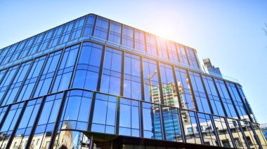 Gökyüzü arka planında cam cepheli modern ofis binası. Ofis binasının şeffaf cam duvarı.