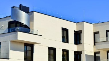 Güneşli bir günde kentsel konut binalarının modern mimarisi. Büyük pencereleri ve geniş terasları olan düşük katlı apartmanlar. Modern bir apartmanın beyaz cephesi.