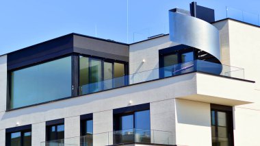 Güneşli bir günde kentsel konut binalarının modern mimarisi. Büyük pencereleri ve geniş terasları olan düşük katlı apartmanlar. Modern bir apartmanın beyaz cephesi.