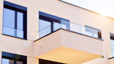 Güneşli bir günde kentsel konut binalarının modern mimarisi. Büyük pencereleri ve geniş terasları olan düşük katlı apartmanlar. Modern bir apartmanın beyaz cephesi.