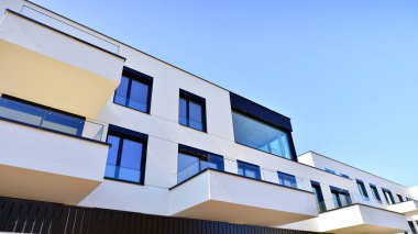 Güneşli bir günde kentsel konut binalarının modern mimarisi. Büyük pencereleri ve geniş terasları olan düşük katlı apartmanlar. Modern bir apartmanın beyaz cephesi.