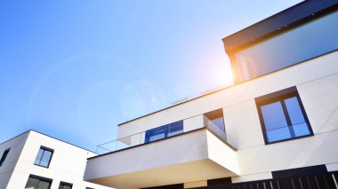 Güneşli bir günde kentsel konut binalarının modern mimarisi. Büyük pencereleri ve geniş terasları olan düşük katlı apartmanlar. Modern bir apartmanın beyaz cephesi.